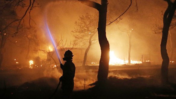 A firefighter sprays water on the fire in the town of Mati, east of Athens.