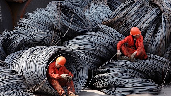 Workers take a break while sitting on a pile of steel wires at a stockyard run by the Shanghai Yirong Trading Co.