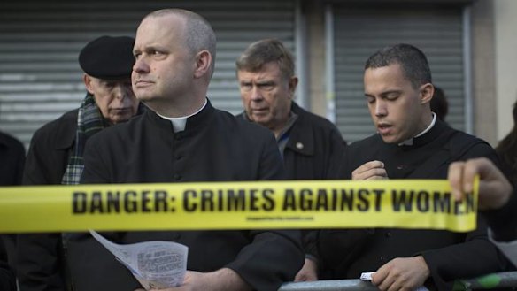 Drawing enemy lines … a pro-choice protester holds a mock police tape in front of anti-abortion priests outside the Choices Women's Medical Centre in New York.