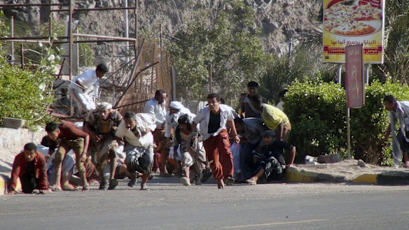 Yemenis run from gunfire at an army base in Aden.