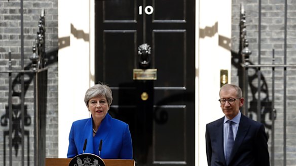 British Prime Minister Theresa May addresses the press in Downing street as her husband Philip looks on.