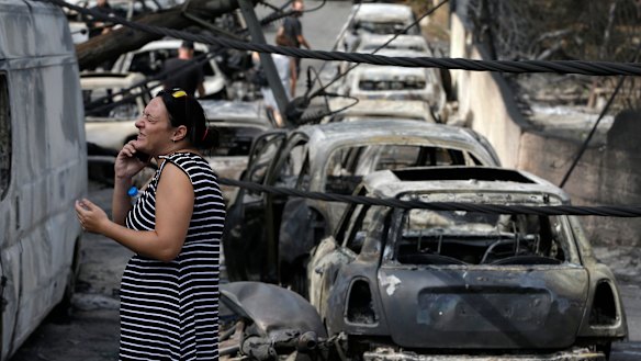 A woman stands amid the charred remains of burned-out cars in Mati.
