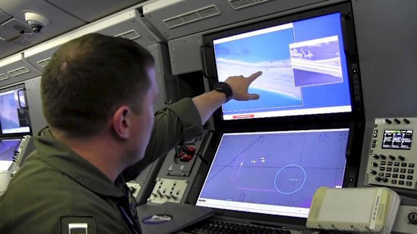 A US Navy crewman aboard a P-8A Poseidon surveillance aircraft views a computer screen purportedly showing Chinese construction on the reclaimed land of Fiery Cross Reef in the disputed Spratly Islands in the South China Sea.