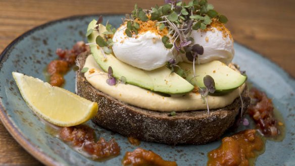 Avocado and hummus on rye with poached eggs, honey-candied bacon and dukkah at The Jetty Oxford, Bulimba.