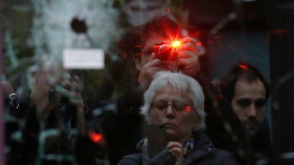 Onlookers photograph bullet holes in the door of Salle a L'etage, one of the sites of the terrorist attacks in Paris.