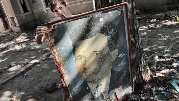 A young Romanian holds a portrait of late Romanian dictator, Nicolae Ceausescu, as he collects scrap to be sold from a house to be demolished in Bucharest.