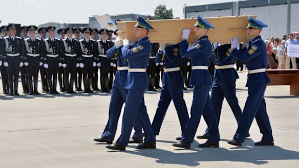 Ukrainian soldiers carry a coffin of one of the MH17 victims on to a military plane at Kharkiv airport.
