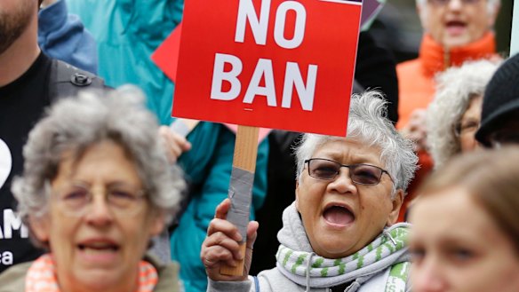 Protesters wave signs and chant during a demonstration in May against Trump's ban.