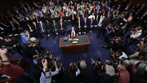 Mr Comey, surrounded by the press, at Thursday's hearing.