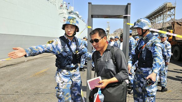 Chinese navy soldiers of the People's Liberation Army (PLA) gesture to Chinese citizens boarding the naval ship Linyi at a port in Aden during their evacuation.