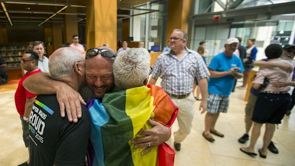 Eric Hause of Norfolk, centre, hugs Claus Ihlemann and Robert Roman in the lobby of the Slover Library Friday morning, in Norfolk, Virginia. 