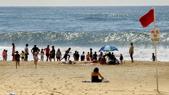 People sit on Nobbys Beach on Tuesday after it was closed.