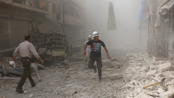 Search and rescue team members run around the debris of damaged buildings after Assad forces and Russian army carried out airstrikes.