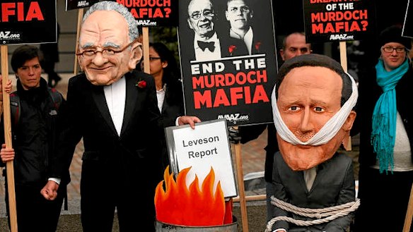 A protest group campaigning against the political dominance of Rupert Murdoch stages a mock burning of a copy of the Leveson Report outside the Queen Elizabeth II centre in London.