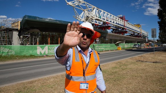 A security guard attempts to stop photographs of the buckled span on the Skytrain viaduct in Sydney's north-west.