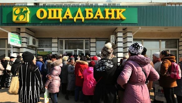 Large crowds gather at the entrance of the Oschadbank in the town of Djankoy.