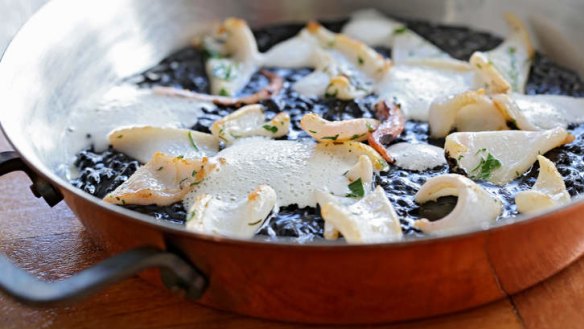 Spanish-style squid with ink-dyed rice served in a copper pot.