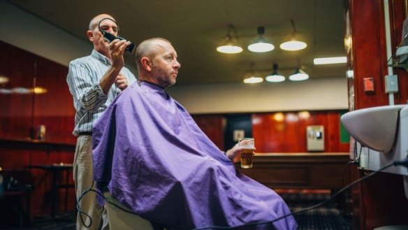 Barber Sergio Talarico gives Peter Docherty a trim while he relaxes with a beer.