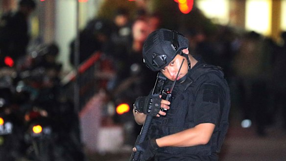 An Indonesian police officer stands guard in front of an apartment building after an explosion in Sidoarjo, East Java.