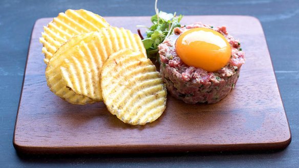 Steak tartare with egg yolk and latticed potato chips.