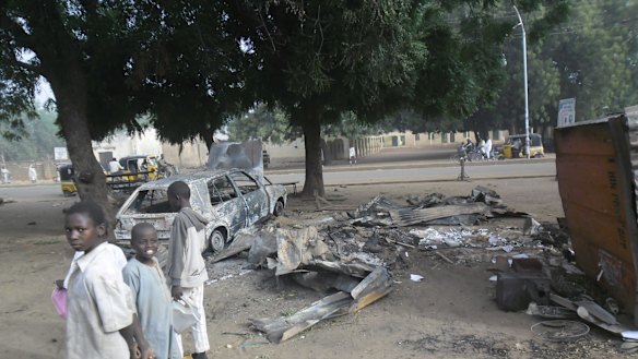Children stand near the scene of an explosion in a mobile phone market in Potiskum, Nigeria ... two females were used as human bombs to target a busy marketplace, killing four people.
