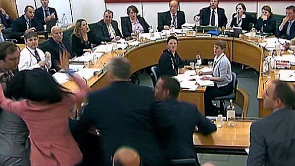 Lunging to her husband's defence ... Wendi Deng, dressed in pink, swings her right arm at her husband's attacker.