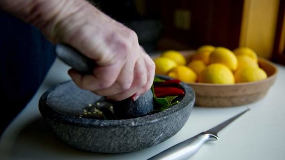 Melting pot ... Neville Bleakley grinds home-grown kaffir lime leaves with chilli using traditional Balinese mortar and pestle called a "cobek".