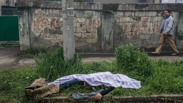 The body of a man killed in the clash between Ukraine and pro-Russian forces lies along the street near a police station that was attacked and burned in Mariupol.