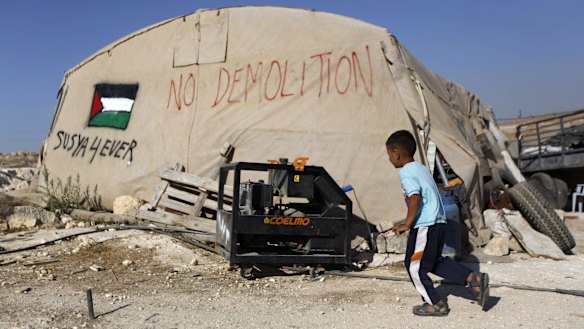 A Palestinian boy runs outside his family tent in Susiya. The people of the village have been displaced onto their own agricultural lands.