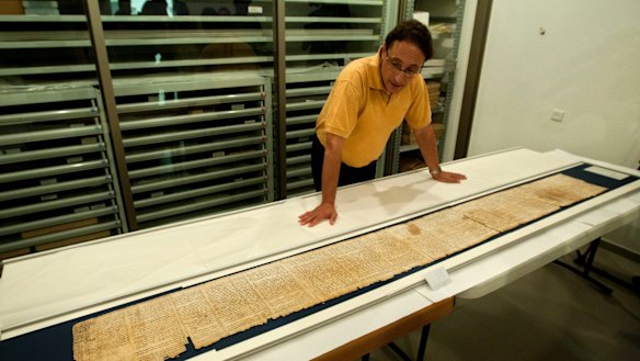 Dr. Adolfo Roitman presents a part of the Isaiah Scroll, one of the Dead Sea Scrolls, inside the vault of the Shrine of the Book building at the Israel Museum in Jerusalem. 