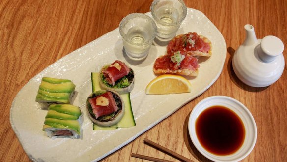 A tuna tasting plate with rolls, taco, tataki and sake.