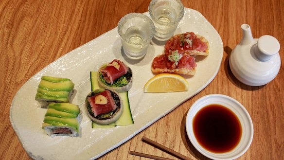 A tuna tasting plate with rolls, taco, tataki and sake.