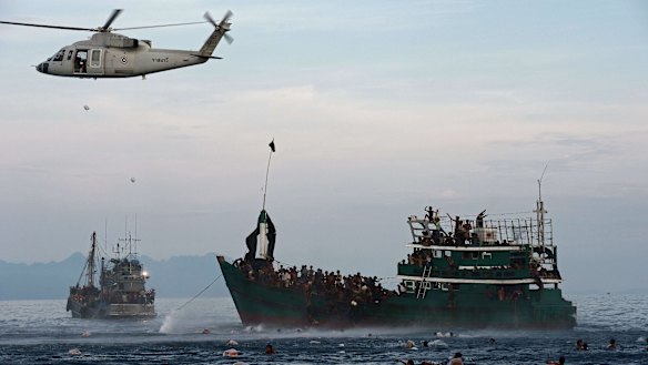 Rohingya swimming to collect food supplies dropped by a Thai army helicopter.