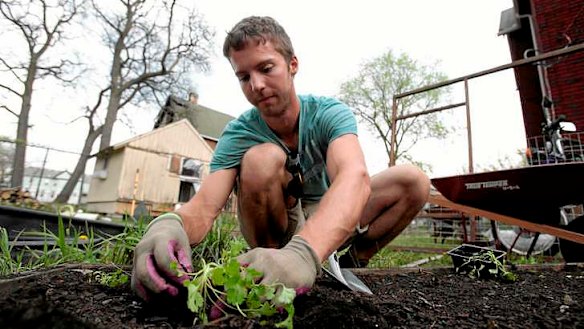 Darin McLeskey plants a vegetable garden in the back yard of one of the properties he purchased for bargain price and plans on refurbishing in Detroit, Michigan.
