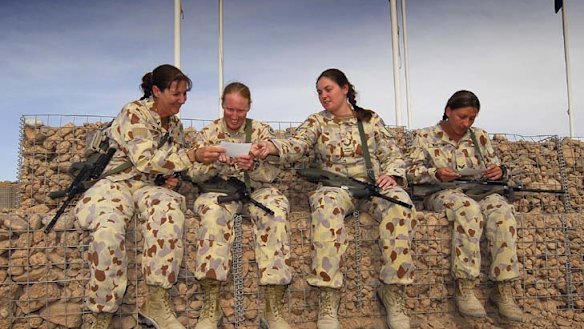 Comrades in arms … Sergeant Donna Bourke, Warrant Officer Cassandra Jones, Corporal Nicole Spohn and Corporal Ivona Bartusch share photos of their children while serving in Afghanistan.