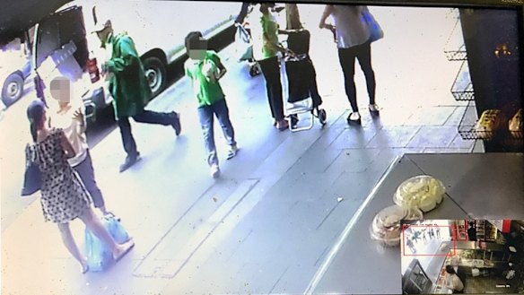 CCTV showing the suspect, wearing a hat and green raincoat, walking towards the Happy Cup cafe at Bankstown.
