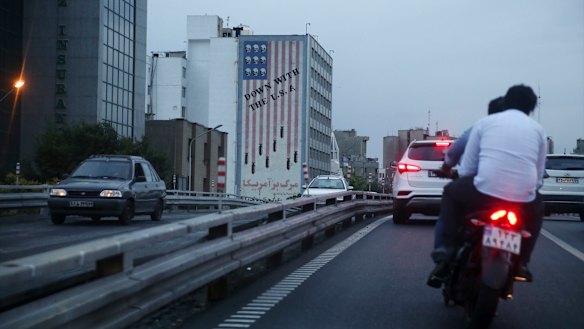 Vehicles drive past an anti-American mural in central Tehran on Tuesday.