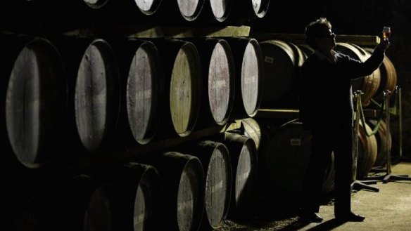 An employee of Scotland's Dalwhinnie distillery views whisky drawn from a cask.