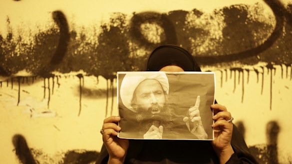 An anti-government protester in Bahrain holds a picture of Sheikh Nimr during clashes between police and protesters in Sanabis.