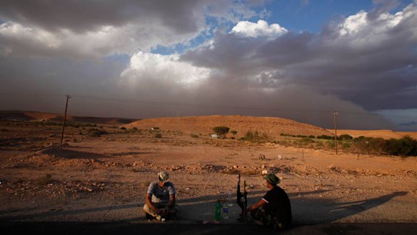 As the shadows lengthen and a sandstorm gathers, anti-Gaddafi fighters sit it out at Wadi Dinar, a checkpoint near Bani Walid.