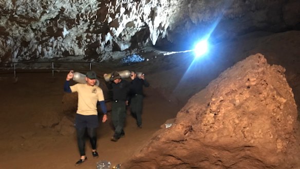 Rescue workers take oxygen tanks into the cave complex.