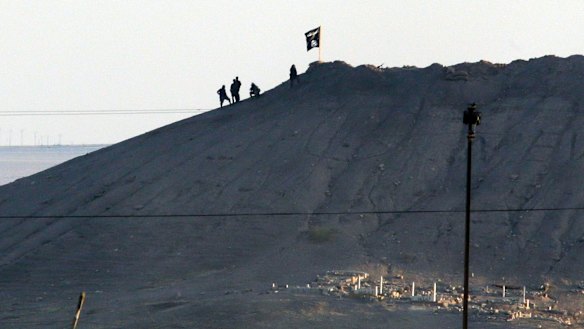 The black flag of Islamic State flies over the town of Kobane in Syria in October 2014.