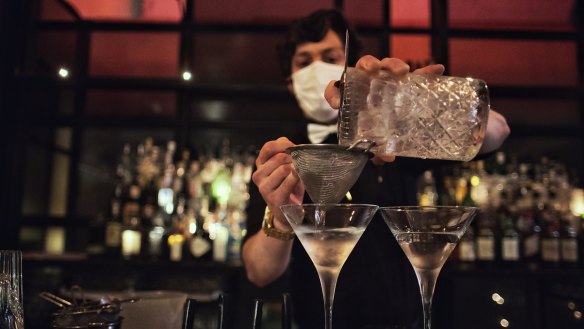 Observing guidelines, a masked bartender mixes a drink at The Supper Club in Melbourne.