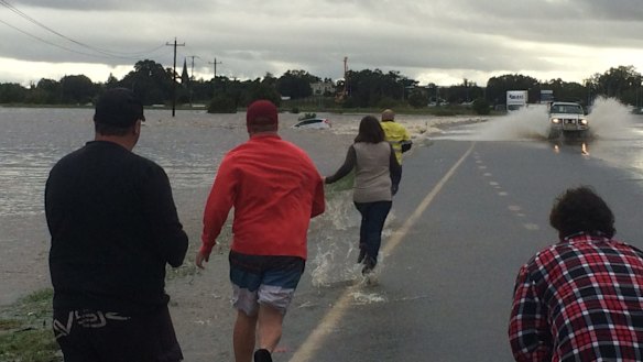 Rescuers rush to a car that is stranded in flood waters in Maitland.