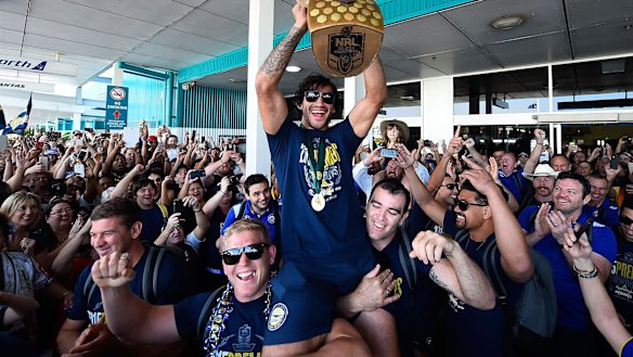 Johnathan Thurston of the Cowboys is hoisted onto the shoulders of Ben Hannant and Kane Linnett with the NRL trophy after arriving back at Townsville airport.
