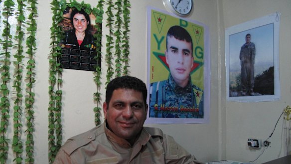 Hamid Derik, who is training new conscripts to Rojava's army, sits under a picture of 22-year-old Arin Mirkan, who ran into a group of Islamic State soldiers and blew herself up.