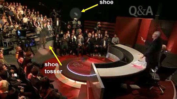 Hunter Valley man Peter Gray tosses his second shoe in the direction of John Howard as Tony Jones stands up to call for the man's removal.