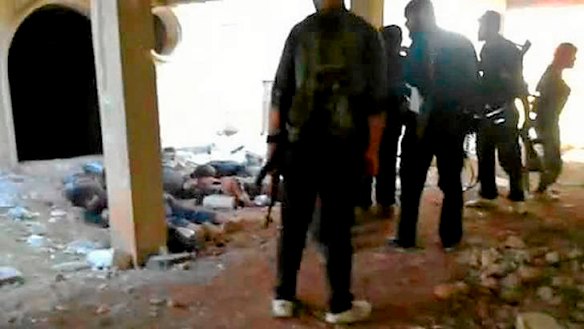 An image grab taken from a video uploaded on YouTube which purports to show rebel fighters gathered near the bodies of Syrian soldiers after they overran an army checkpoint in the northwestern Idlib province.