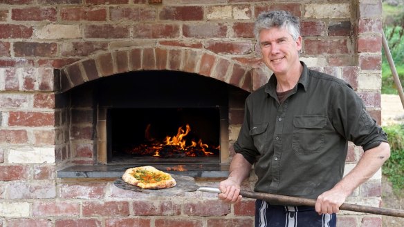 Matthew Evans cooking pizza in Dennis the brick oven.