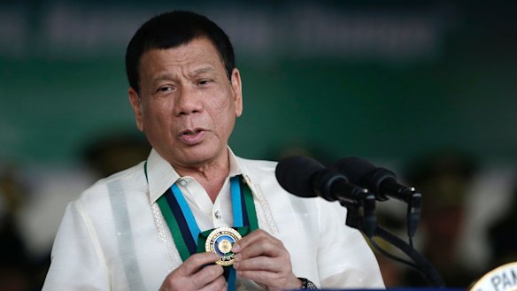 Philippine President Rodrigo Duterte shows a medal during his speech to troops in Quezon City in December.